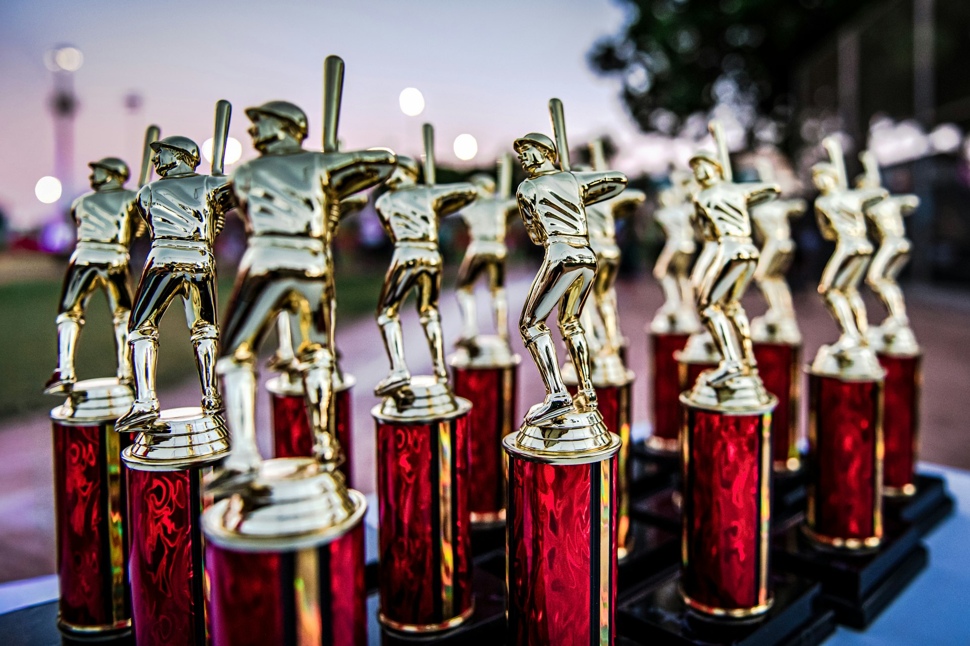 Collection of baseball trophies displayed outdoors at dusk.